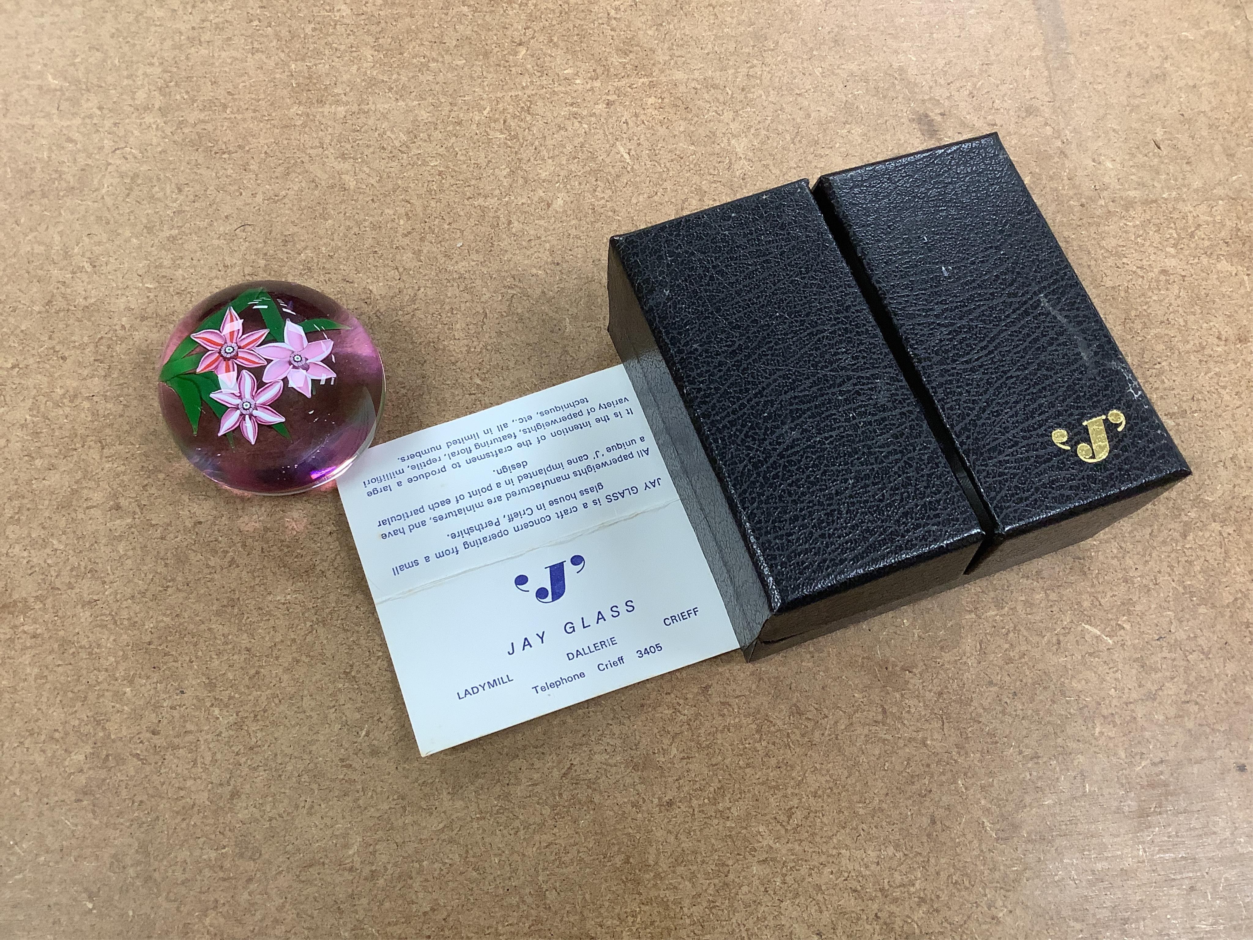 Two Perthshire lamp work glass paperweights, fruit weight, 52/350, rose and bud weight, 69/300 together with a John Deacons bouquet on a ruby base paperweight, edition of 101 (3)